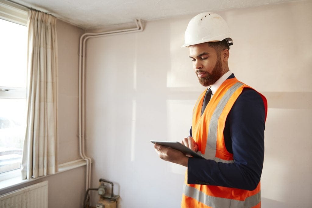 environmental health improvement - man inspecting house with tablet