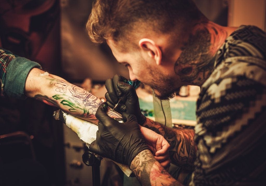 改善环境卫生——纹身师在手臂上纹身