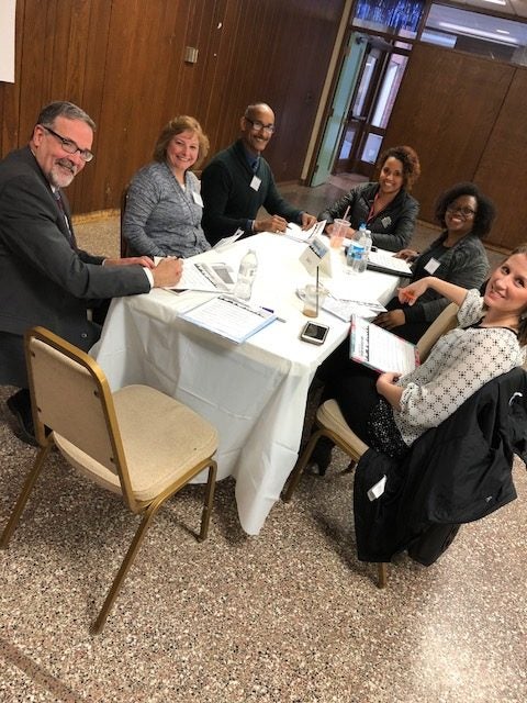 trauma informed community - smiling group of people at a table
