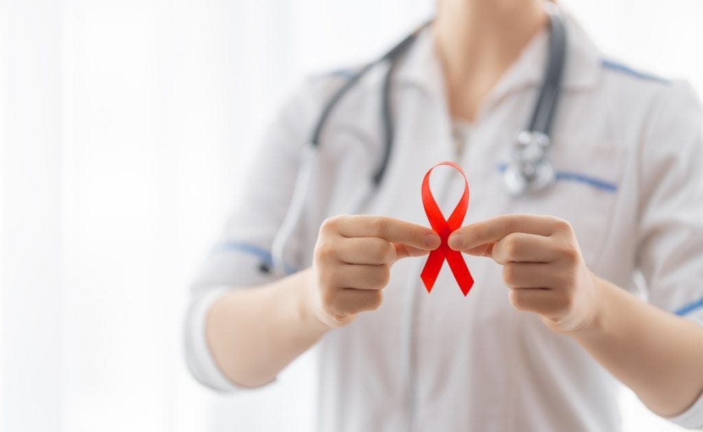 HIV care - person holding up a red ribbon