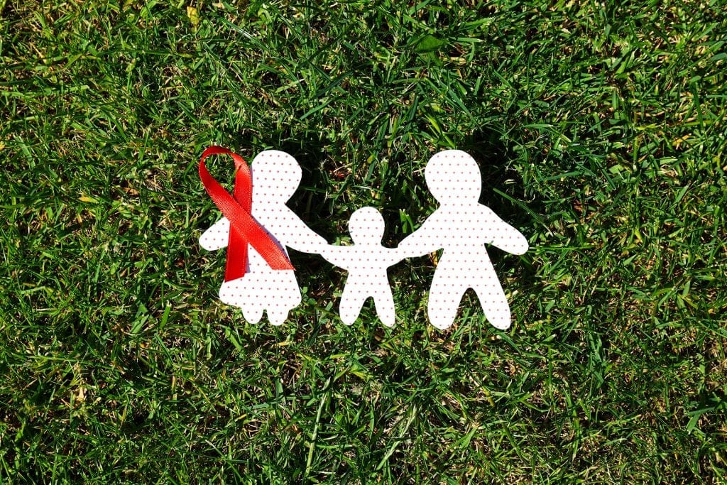 health protection - paper cut out of family with a red ribbon